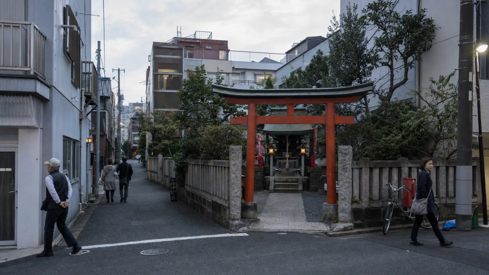 Calle de Tokio al atardecer con un santuario pequeño entre edificios contemporáneos